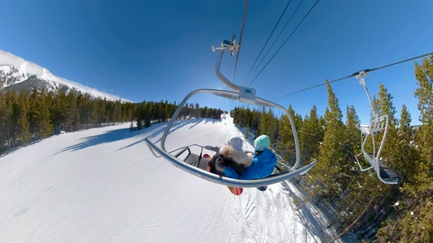 年轻的滑雪板手在阳光明媚的日子里乘坐缆车观察风景视频素材模板下载