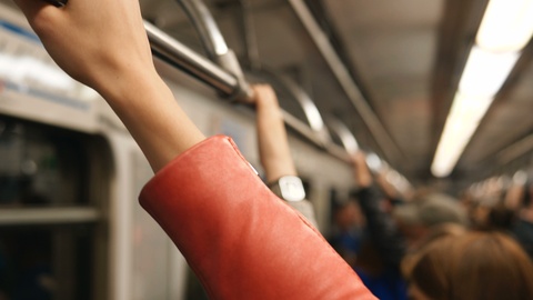 女孩手戴着橙色皮夹克抓住地铁扶手