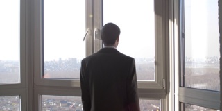 年轻成功的商人站在窗前眺望远方
