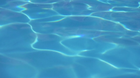 酒店度假村游泳池里的蓝色水抽象，超慢动作。