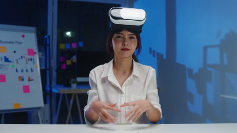 年轻的亚洲女设计师正在使用VR眼镜测试开发的移动应用程序