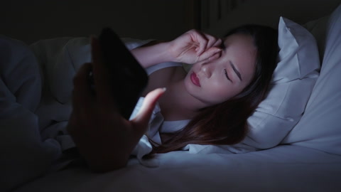 特写女人晚上在床上使用智能手机眼睛疼痛