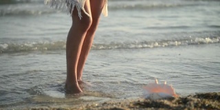 日落时分，女人在海水上跳舞的腿特写