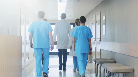 医生、护士和助理团队穿过大厅的后视图