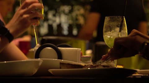 朋友们在餐厅里享用牛排和品尝葡萄酒，餐盘和手靠近