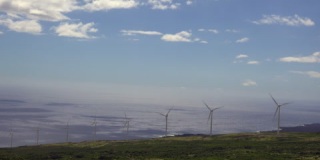 4K风力涡轮机在俯瞰浩瀚海洋的山坡上旋转