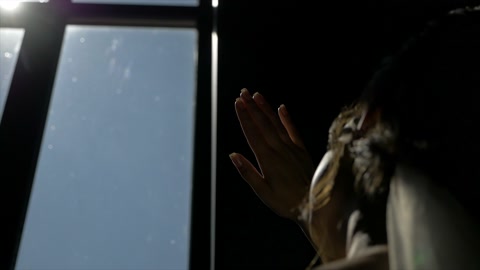 一个女孩在黑暗房间里，用手遮住了太阳视频素材模板下载