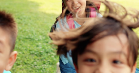 一群小学生朝着手机镜头在草地上奔跑