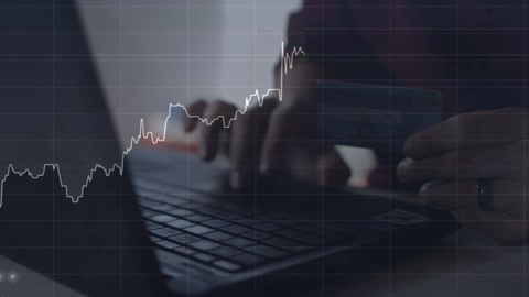 高加索男子在桌子上使用笔记本电脑进行工作，显示着财务图表