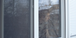 沮丧的男人站在窗边看着外面