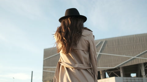 年轻美丽的女孩走在街上她是一位黑发长发的棕色美女，戴着黑色帽子