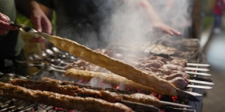 街头食物，厨师在热煤和烟雾中准备烤架上的快餐，特写