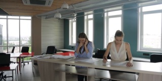 两个女人站在办公桌前在办公室工作