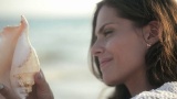 女人黑发听一个大美丽的海贝微风附近的耳朵高清在线视频素材下载