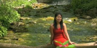 春天，穿着红色连衣裙的亚洲女人坐在河边