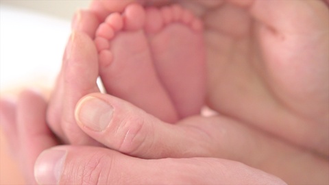 宝宝的脚在父母的手中特写镜头下的新生儿小脚在手上视频素材模板下载