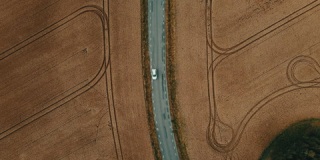 两辆汽车在麦田之间的道路上相互超越的空中镜头