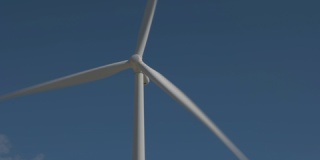 一个大型现代风力发电机近距离拍摄，它旋转并产生能量