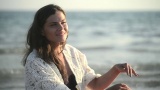 漂亮的女人黑发坐在一个日落海滩上看着一个地平线高清在线视频素材下载