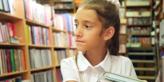 一个8-12岁女孩的肖像，站在图书馆里。一个书架