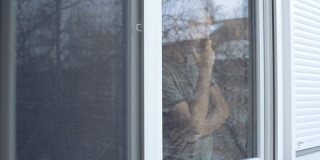 沮丧的男人站在窗边看着外面
