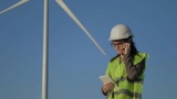 绿色能源检查员在风力涡轮机前打电话高清在线视频素材下载