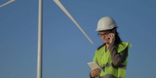 绿色能源检查员在风力涡轮机前打电话