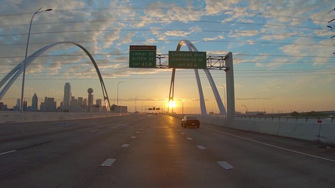 日落时分驾驶POV到现代城市有漂亮的云和拱桥