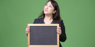 成熟美丽的亚洲女商人思考同时显示黑板