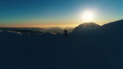 空中跟踪拍摄成年男性登山者在雪山顶上行走