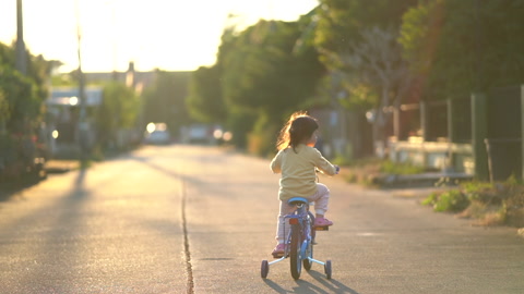 日落时分小女孩在道路上骑自行车