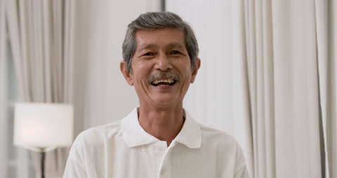 近距离拍摄的亚洲老年灰发男性的面部肖像，他对着相机微笑
