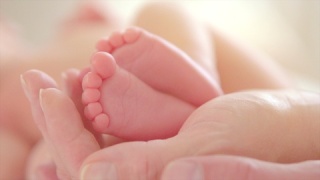 家长手中的宝宝脚近距离拍摄的婴儿小小的脚在手上视频素材模板下载