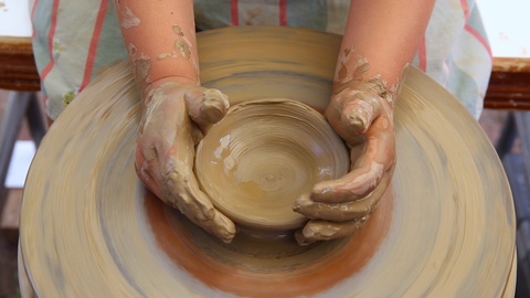 小孩子用陶瓷轮制作陶罐，孩子正在学习陶艺