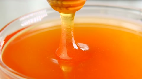 蜜蜂勺玻璃杯中蜂蜜的棍子，慢动作治愈甜点视频素材模板下载