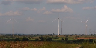 风力发电机高耸在农田上，农民种植庄稼并照料