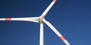 蓝天上旋转风力涡轮机的特写镜头。