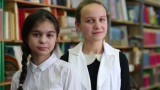 两个女孩站在图书馆的书架前高清在线视频素材下载