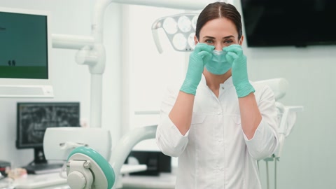 一名高兴的女牙医正在摘下她的医用口罩，望向镜头视频素材模板下载