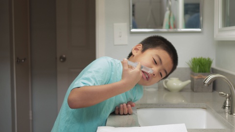 年轻的亚洲男孩在家用盐水和注射器做鼻窦冲洗