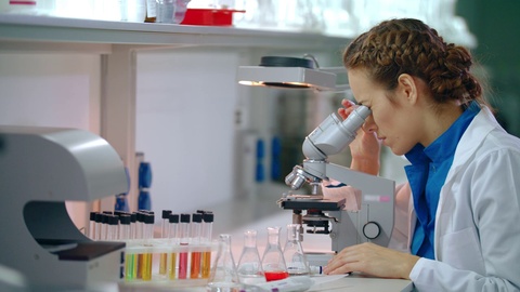 女性科学家在使用显微镜进行研究女性科学家正在观察显微镜视频素材模板下载