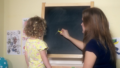 女教师在粉笔黑板上为小女孩写数字视频素材模板下载