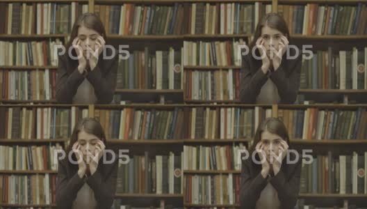 女学生，图书馆。悲伤的女孩站在图书馆的书架前高清在线视频素材下载
