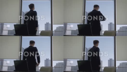 导演在办公室站在窗口，看着他的手表高清在线视频素材下载
