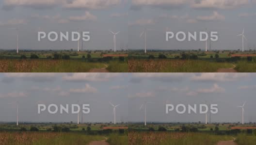 风力涡轮机高耸在农田上，农民在种植作物并照料高清在线视频素材下载