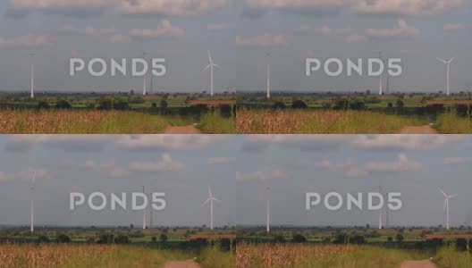 风力发电机高耸在农田上方，农民们种植庄稼并耕作高清在线视频素材下载