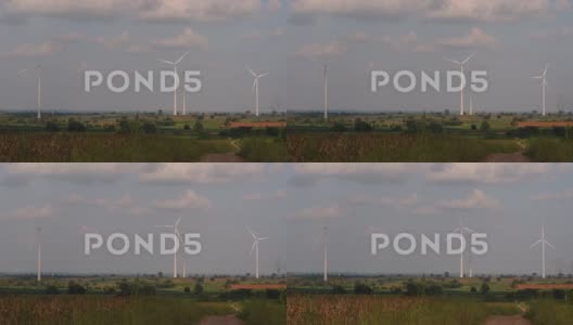 风力涡轮机高耸在农田上方，农民正在种植庄稼并进行耕作高清在线视频素材下载
