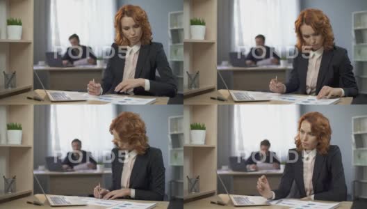 公司的女员工坐在办公桌前，检查图表，思考结果高清在线视频素材下载