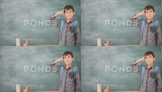 小男孩在教室黑板前思考高清在线视频素材下载