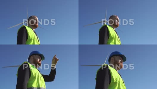 风车附近戴着安全帽的成年工人高清在线视频素材下载